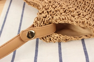 Détail du sac tressé en corde de papier avec bandoulière en cuir et bouton doré chic