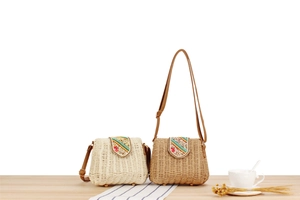 Detail of paper straw woven crossbody bags with colorful beadwork and leather straps