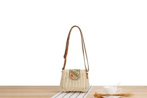 Detailed shot of the colorful bead embroidery on a woven straw crossbody bag