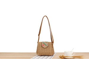Detailed close-up of handmade straw woven crossbody bag with ethnic floral embroidery