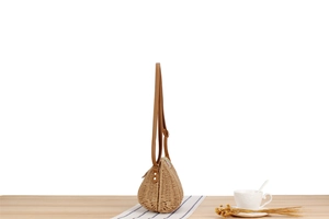 Side view of woven paper straw crossbody bag showing texture and leather strap details