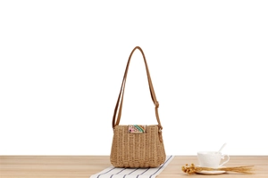 Detail of hand-woven paper rope crossbody bag with colorful striped flap and leather strap