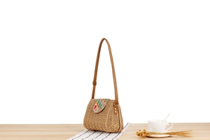 Detail of colorful ethnic embroidery and beadwork on straw woven crossbody bag