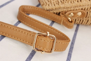 Detail of brown PU shoulder strap with gold metal buckle on woven paper string bag