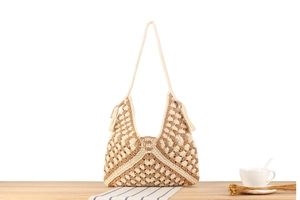 Dettaglio della borsa a tracolla boho intrecciata con motivi geometrici e nappe