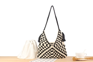 Dettaglio della borsa hobo in maglia bohémien con motivi a rombi neri e bianchi e nappe