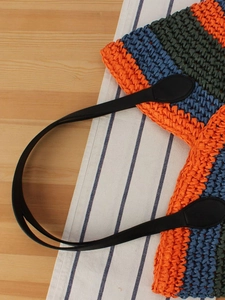 Colorful handmade woven straw tote bag with striped pattern and black leather handles