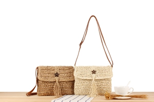 Detail of woven straw bags with star wood buttons and tassel accents in two colors