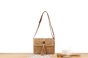 Detail of bohemian straw woven bag with wooden star charm and long fringe tassel
