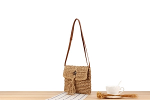 Detail of woven straw shoulder bag with long fringe tassels and star-shaped button
