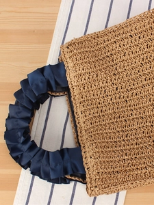 Handmade straw tote bag with navy blue satin ruffled handles for summer beach vacations