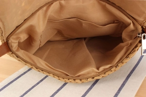 Close-up of woven straw bag interior showing fabric lining and secure zipper closure