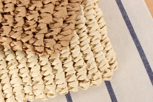Detailed macro view of beige and light brown woven straw bags on blue striped fabric