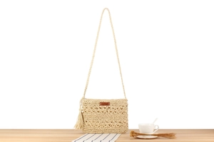 Detailansicht der handgefertigten Strohtasche mit Boho-Quasten und Lederetikett-Akzent