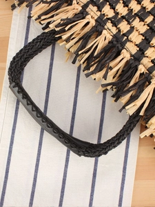Ethnic straw tote bag with black fringe tassels and reinforced leather handle detail