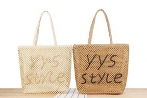 Détail de sacs fourre-tout en paille tressée beige et marron avec lettrage YYS style