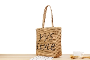 Gros plan sur la broderie YYS sur le sac cabas évidé en paille de papier tissée