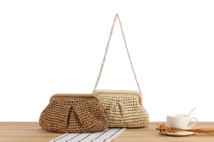 Chic paper rope woven clutch bags with metal chains displayed on a wooden table surface