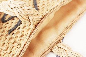 Gros plan d'un sac en papier tressé avec rayures noires et fermeture éclair en métal