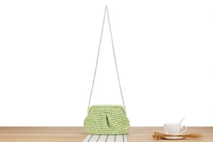 Close-up of green hand-woven paper rope bag with textured knit and gold chain strap