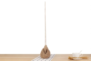 Detail of hand-woven paper rope shoulder bag with fine gold chain strap on wooden table