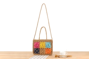 Detail showing the colorful crochet flower patterns and natural straw texture of the handbag