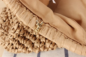 Detailed close-up of woven paper straw texture and vintage gold metal hinge of beach bag