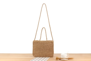Detail of hand-woven straw handbag showing fine sisal fiber texture and leather strap
