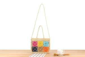 Detailed close-up of handmade woven straw bag with colorful crochet flower decorations