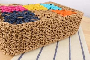 Detailed close-up of woven straw bag side and vibrant 3D crochet flowers on top edge