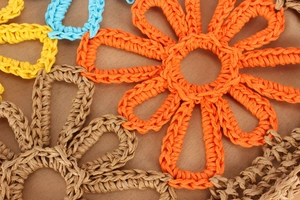 Macro detail of handmade crochet flower patterns on a straw woven handbag strap