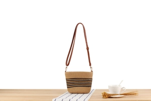 Detailed macro of a straw woven bag featuring black stripes and a leather strap