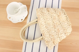 Close-up of handwoven corn husk tote bag with dense texture on a wooden table