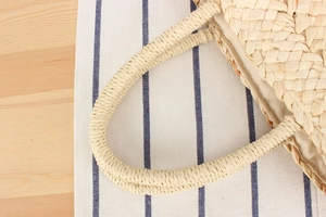 Detail shot of hand-woven corn husk straw bag handles and fine fabric lining texture