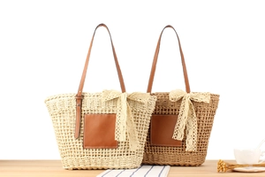 Close-up of woven straw tote bags with delicate lace bows and leather details
