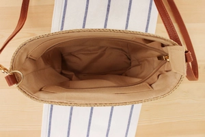 Detailed interior of woven straw bag showing the zipper pocket and light brown lining