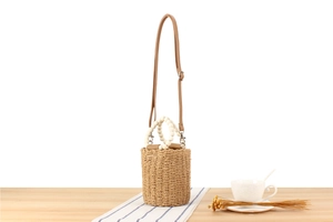 Detail of bohemian paper rope woven bucket bag with white bead handle and leather strap