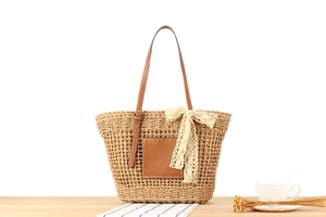 Detailed texture of woven straw beach bag with leather patch and lace bow decoration