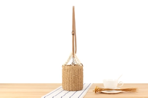 Close-up of woven paper rope texture with wooden bead handles on a summer bucket bag
