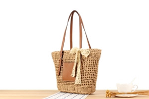 Detail of woven straw tote bag with brown leather handles and decorative lace bow