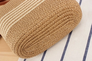 Detailed close-up of woven straw handbag featuring brown and white striped patterns