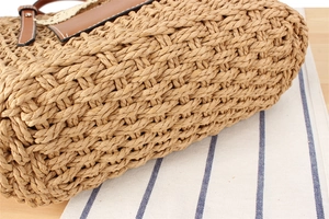 Close-up of hand-woven straw bag texture with lace edge and brown leather handle details