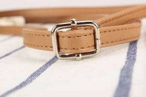 Macro detail of leather strap with silver metal buckle and fine stitching on bucket bag