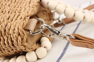 Macro detail of hand-woven straw texture with white beaded handle and silver hardware
