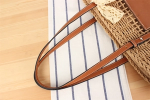 Detail of woven straw tote bag with faux leather handles and delicate lace bow accent