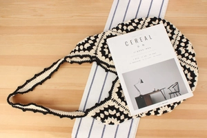 Detail of hand-woven crochet shoulder bag with black and white wavy retro knit texture