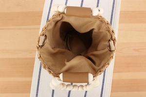 Top view of handmade straw bucket bag with wooden bead handles and khaki fabric lining