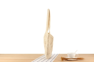 Side view of beige crochet tote bag showing lightweight flat texture and knit pattern