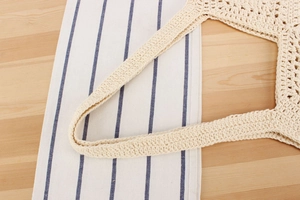 Detail of beige crochet knit tote bag showing intricate woven texture and sturdy handle