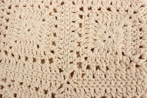 Macro shot of detailed floral crochet pattern on beige oversized knit shoulder bag